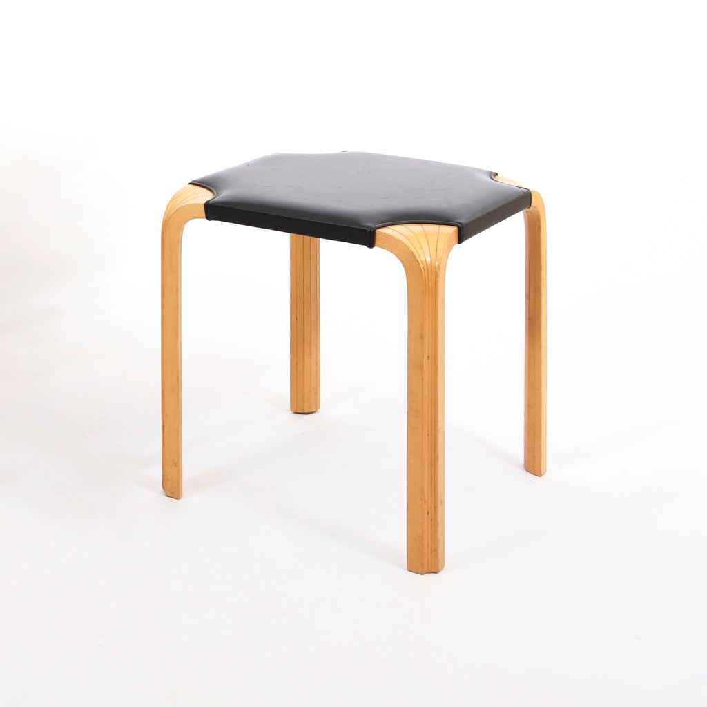 Stool X601 features a solid birch frame with black leather upholstery. The stool is a vintage piece from the Artek 2nd Cycle collection.