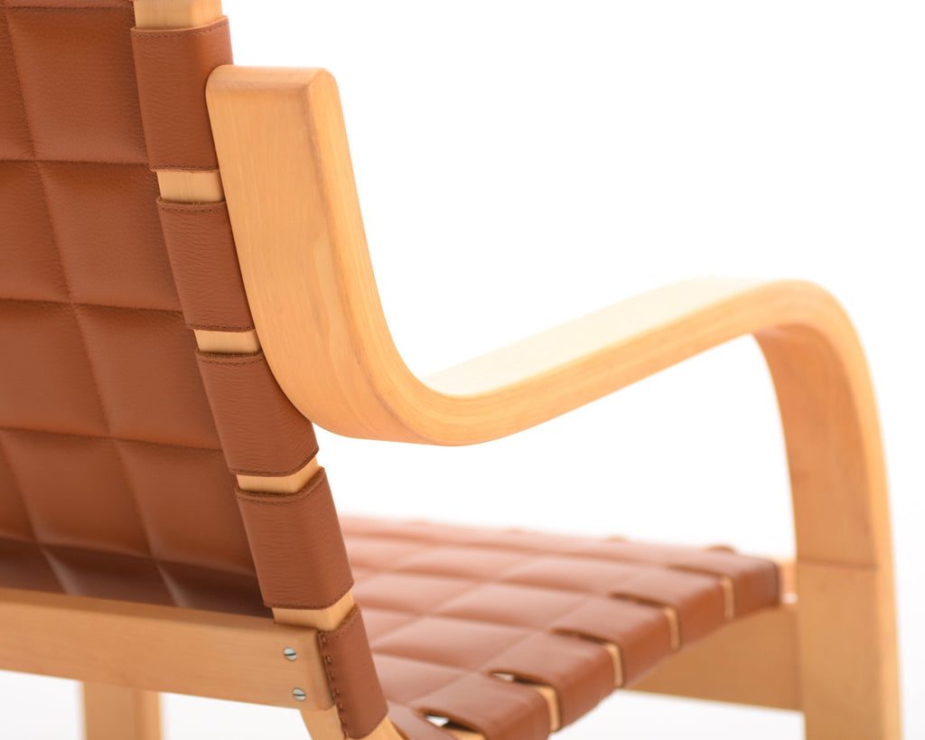 Rear perspective focusing on the birch armrest and the leather upholstery of the armchair.