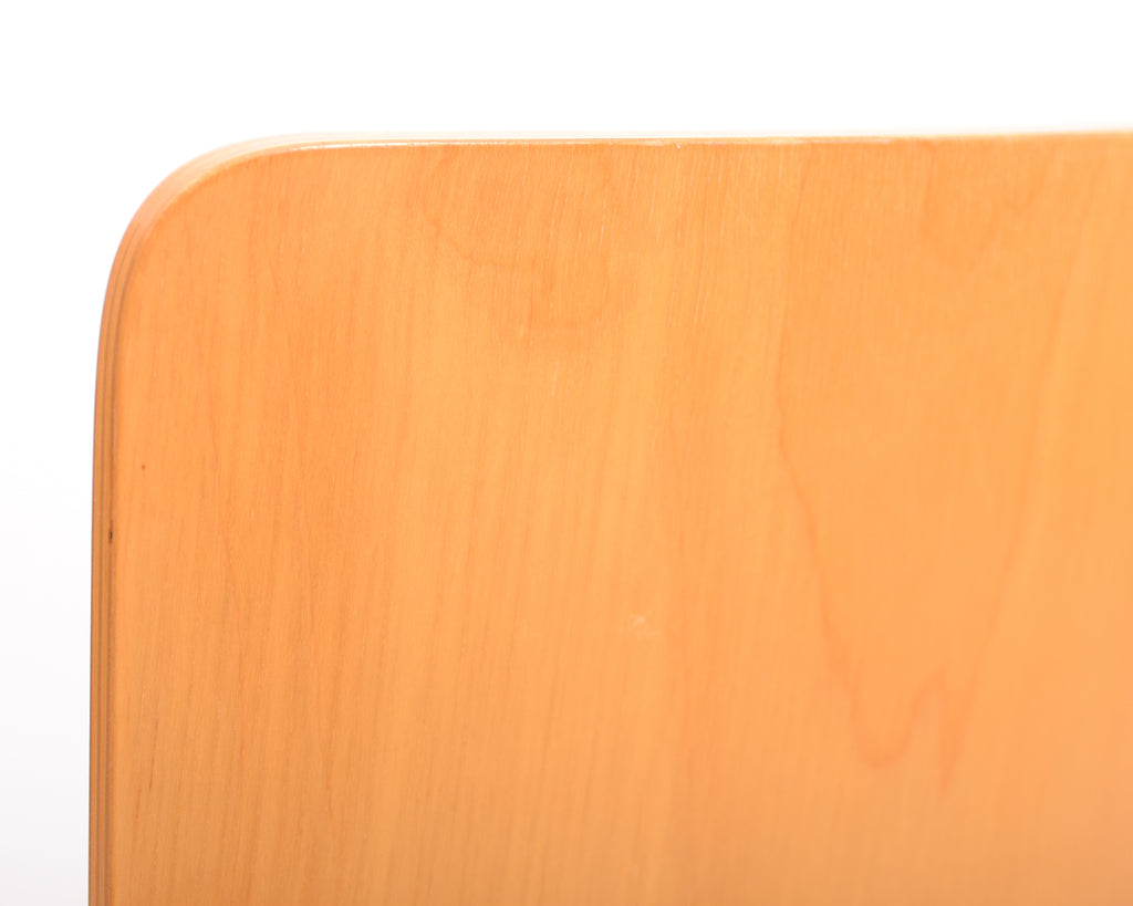 Close-up view of the curved corner of a wooden chair backrest.
