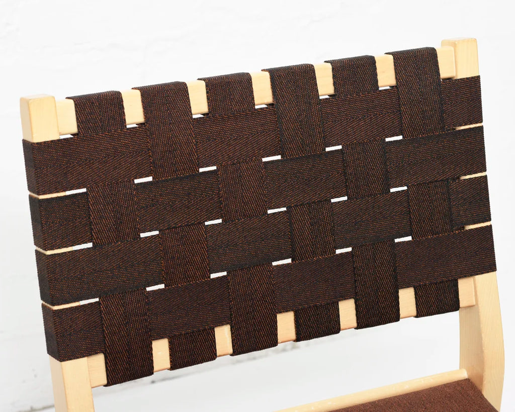 Close-up highlighting the birch frame edges and the backrest re-webbed in brown webbing.