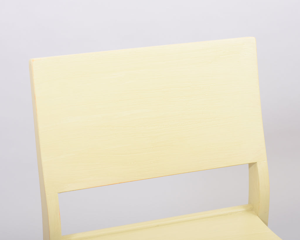 Close-up front view of the Alvar Aalto 611 chair’s backrest, made entirely of wood and painted in light yellow.
