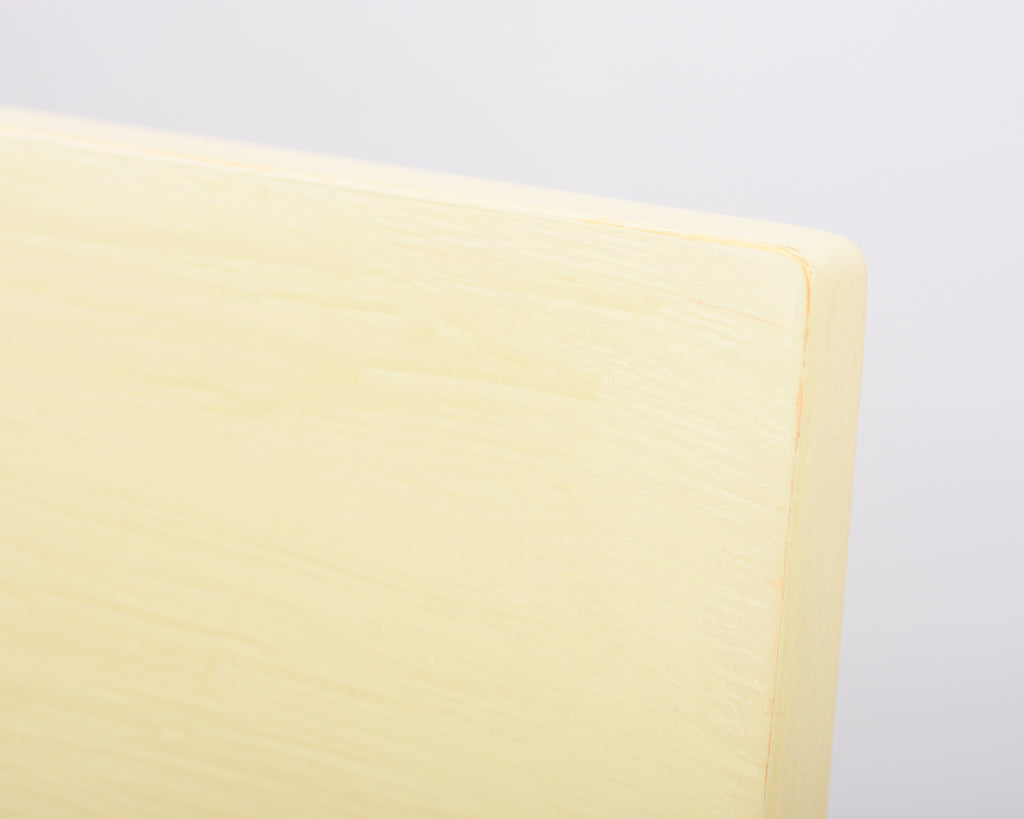 Extreme close-up front view of the Alvar Aalto 611 chair’s backrest, made entirely of wood and painted in light yellow.