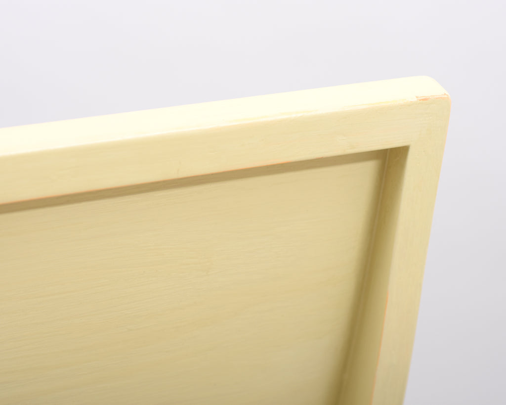 Close-up view of the Alvar Aalto 611 chair’s backrest, made entirely of wood and painted in light yellow.
