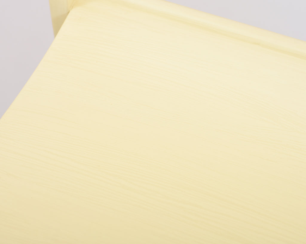 Close-up view of the Alvar Aalto 611 chair’s seat, made entirely of wood and painted light yellow.