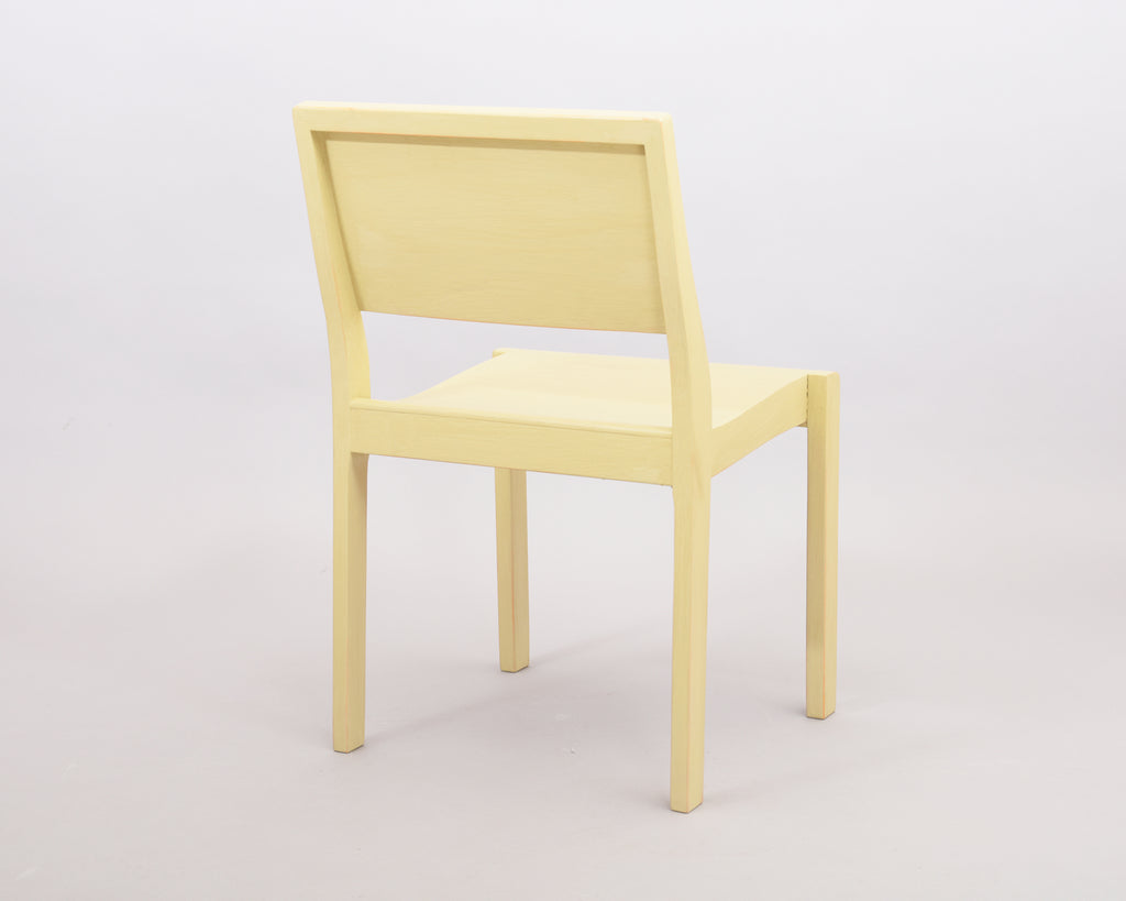 Rear view of the entire Alvar Aalto 611 chair, made of wood and painted light yellow.