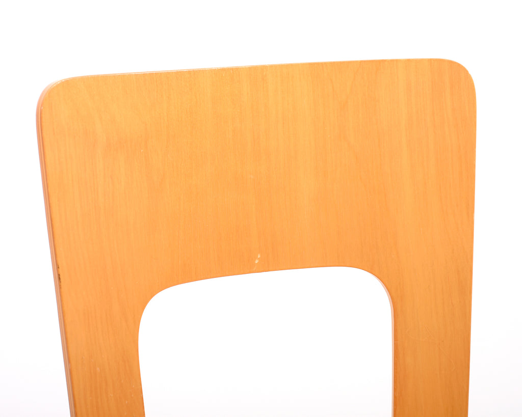 Close-up view of the curved wooden backrest of an Alvar Aalto 66 chair.