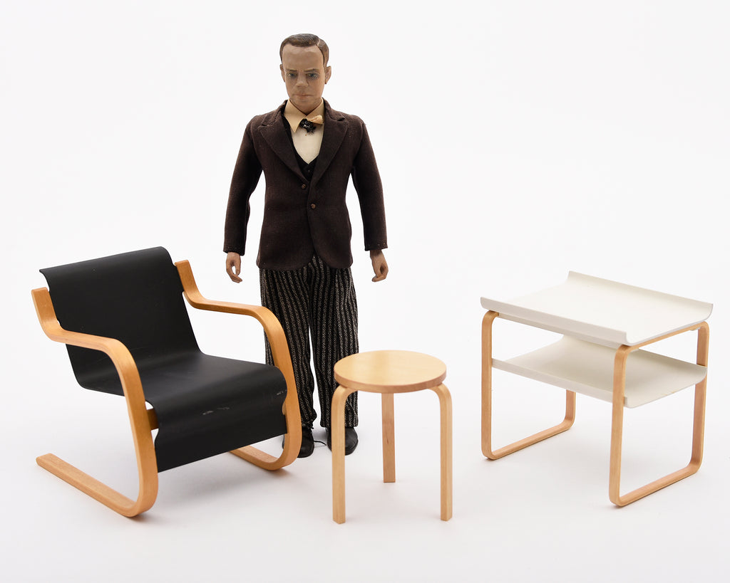 Figure standing next to modern furniture on a white background.