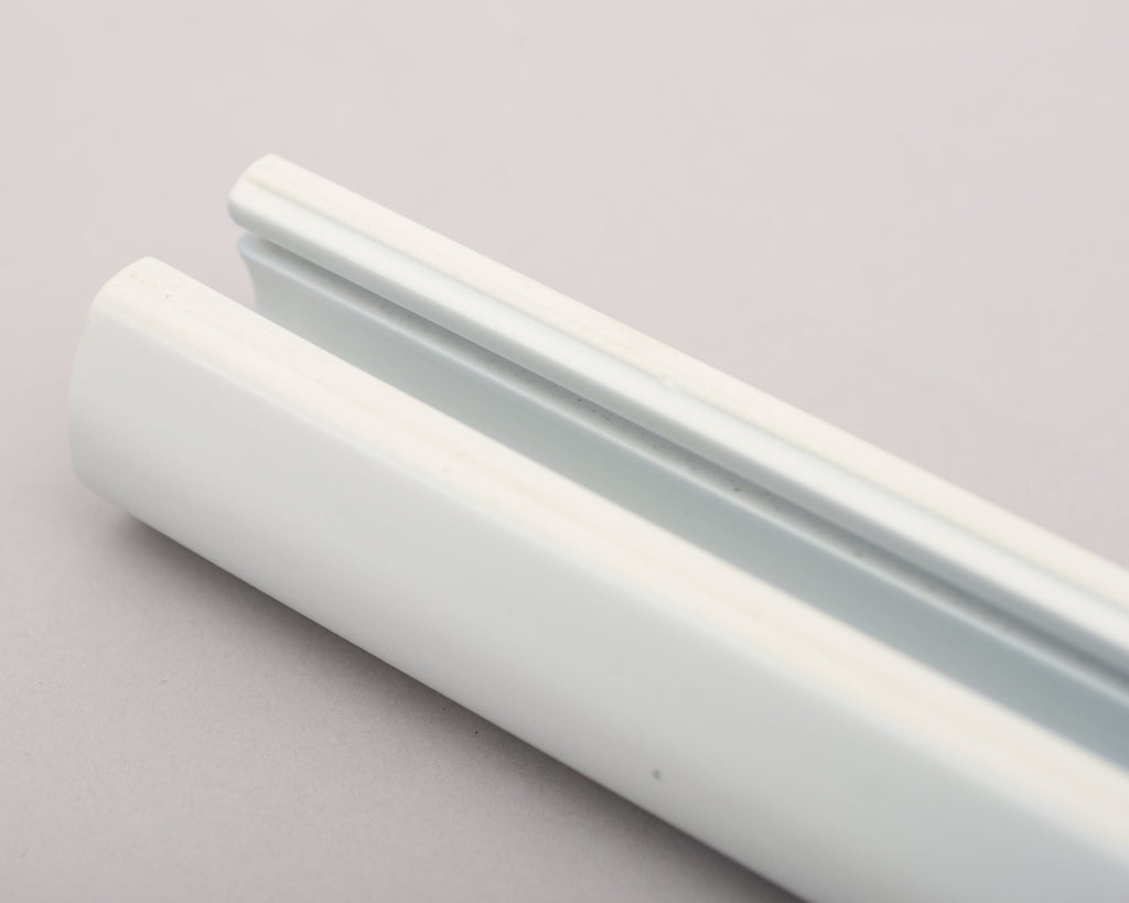 Close-up of the Aalto Glazed Tile Rod placed on a grey surface, showing its interior form and curved shape.