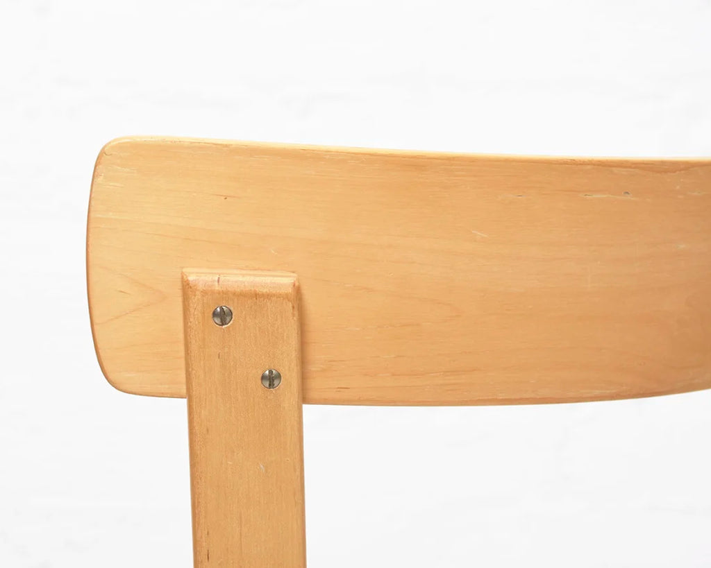 Close-up of the backrest of a wooden chair with a light finish on a white background.