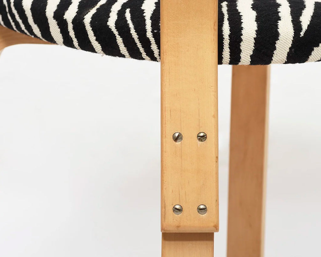 Close-up of a chair seat upholstered with Zebra fabric and wooden details. 