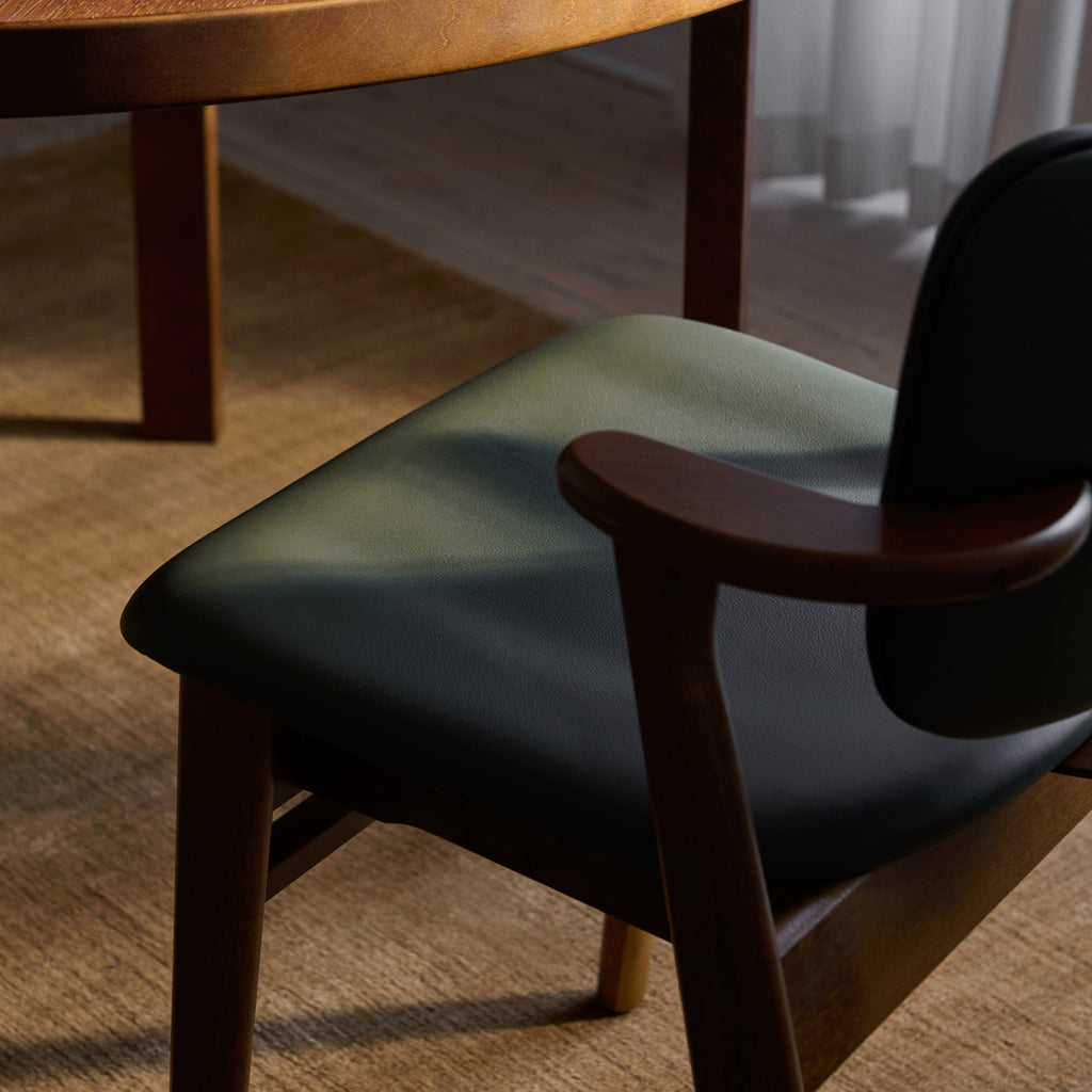 Close‑up top view of the Domus Chair seat, upholstered in dark green Spectrum Moss leather, with a walnut‑stained birch frame.