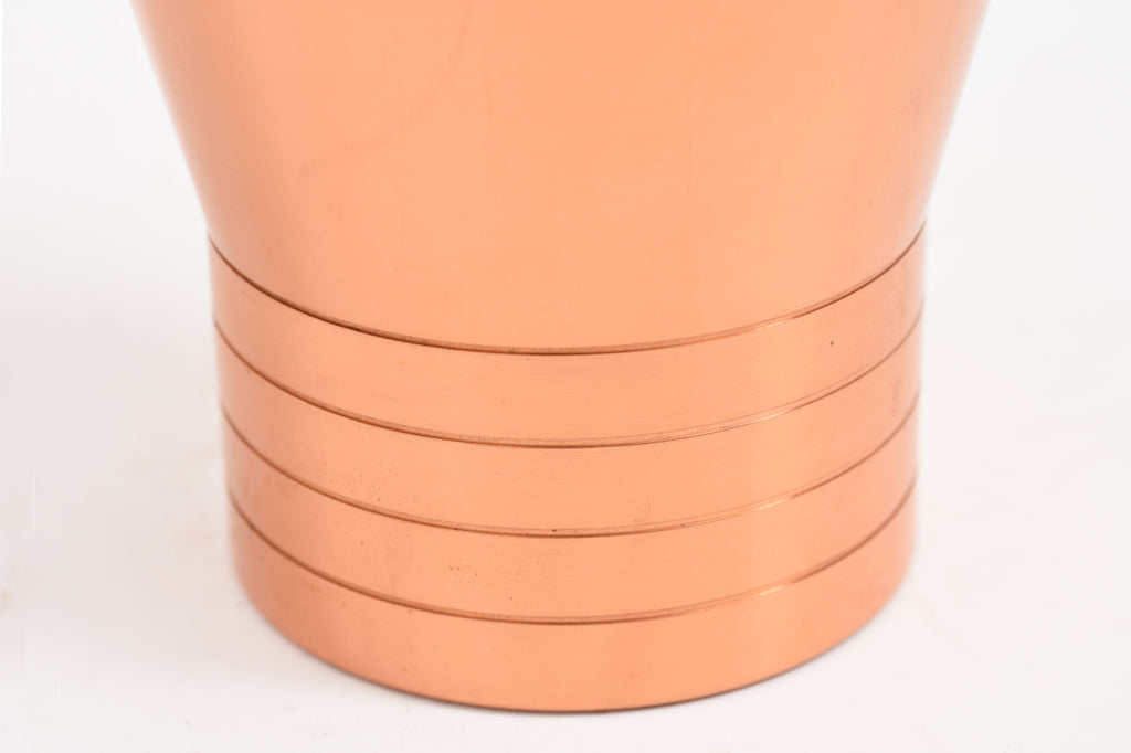 Close-up of the lower part of a copper vase.