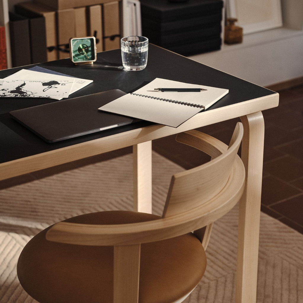 Close-up interior view featuring Aalto Table 80B with a black linoleum top, highlighting the surface material. Rival Chair is paired with the table.