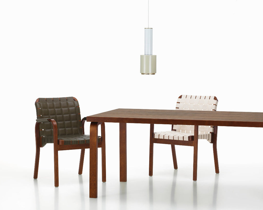 Interior view featuring Aalto Table 83 in walnut stain surrounded by two Armchair 45. Pendant Light A110 “Hand Grenade” in a duo-tone finish is placed above the table.
