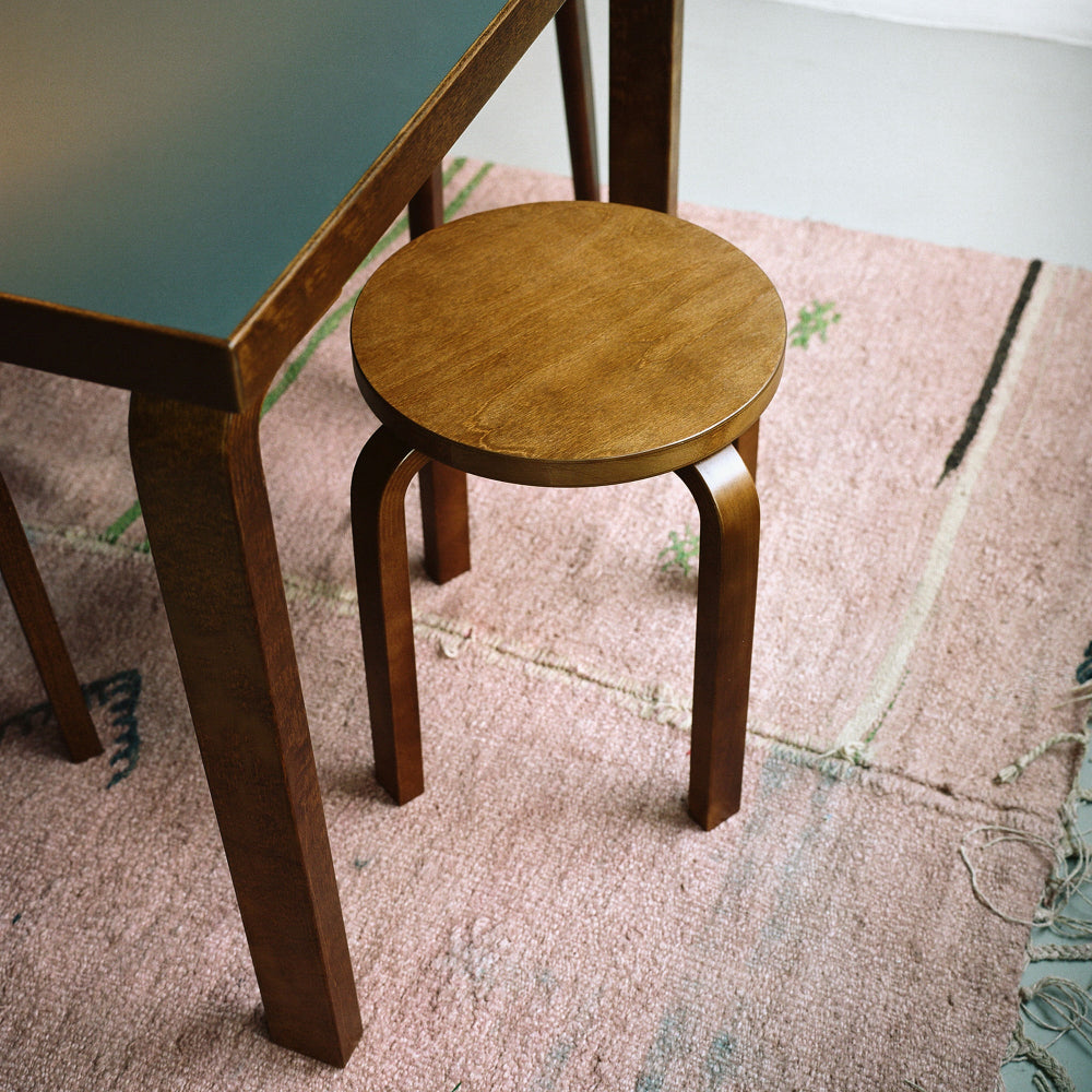Close-up interior view featuring Artek Stool E60 with a walnut stained finish next to a rectangular Aalto Table.