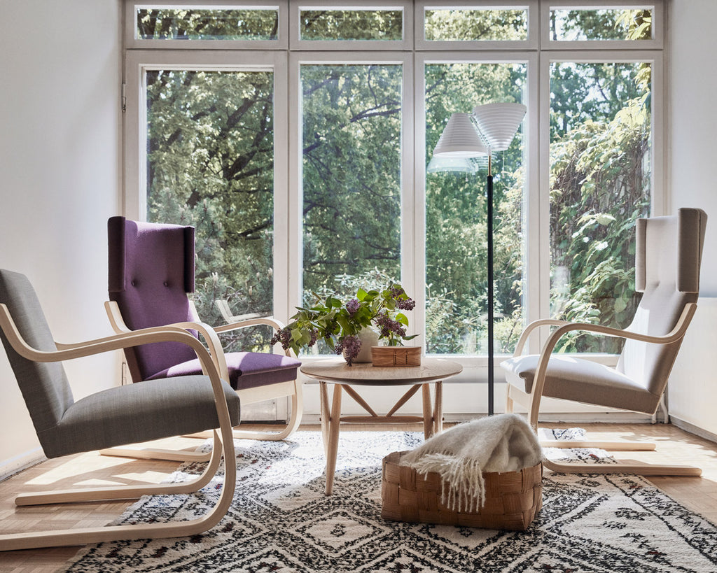 Interior view of a living room featuring Armchairs 401 and Armchair 402 placed around an oak Ovalette Table. Floor Light A810 stands nearby.