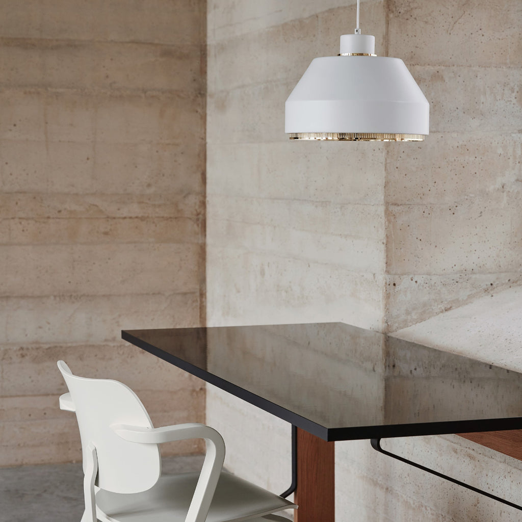 Minimalist interior featuring a Kaari desk used as a workspace, paired with a white Aslak Chair. A white AMA500 pendant light is positioned above the desk and switched off.