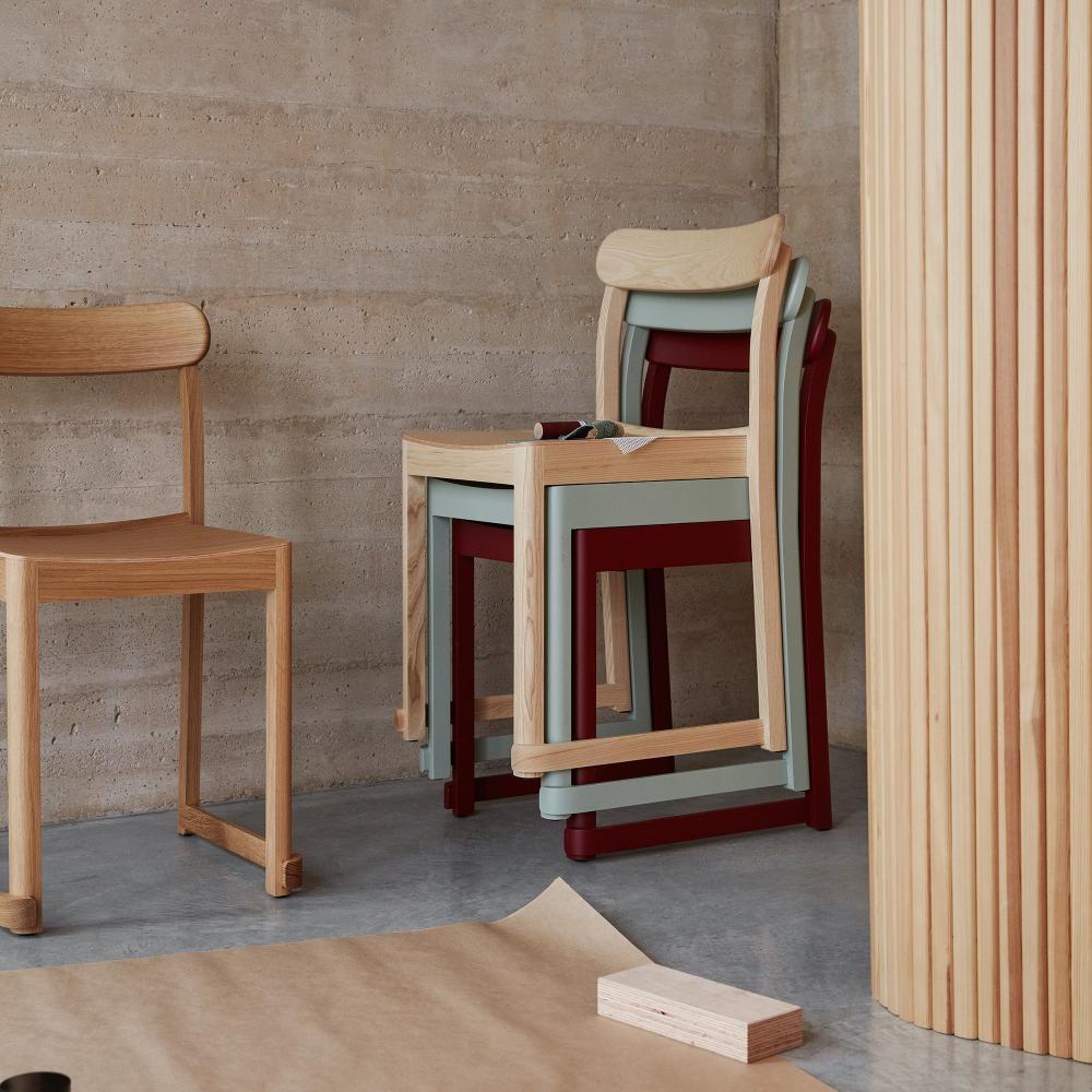 Minimalist interior featuring one Atelier Chair placed in front of a stack of three Atelier Chairs. Screen 100 is visible in the background.