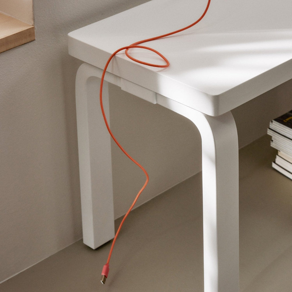 Close-up interior view of a white lacquered Bench 168B. An orange cable is placed on top of the bench.