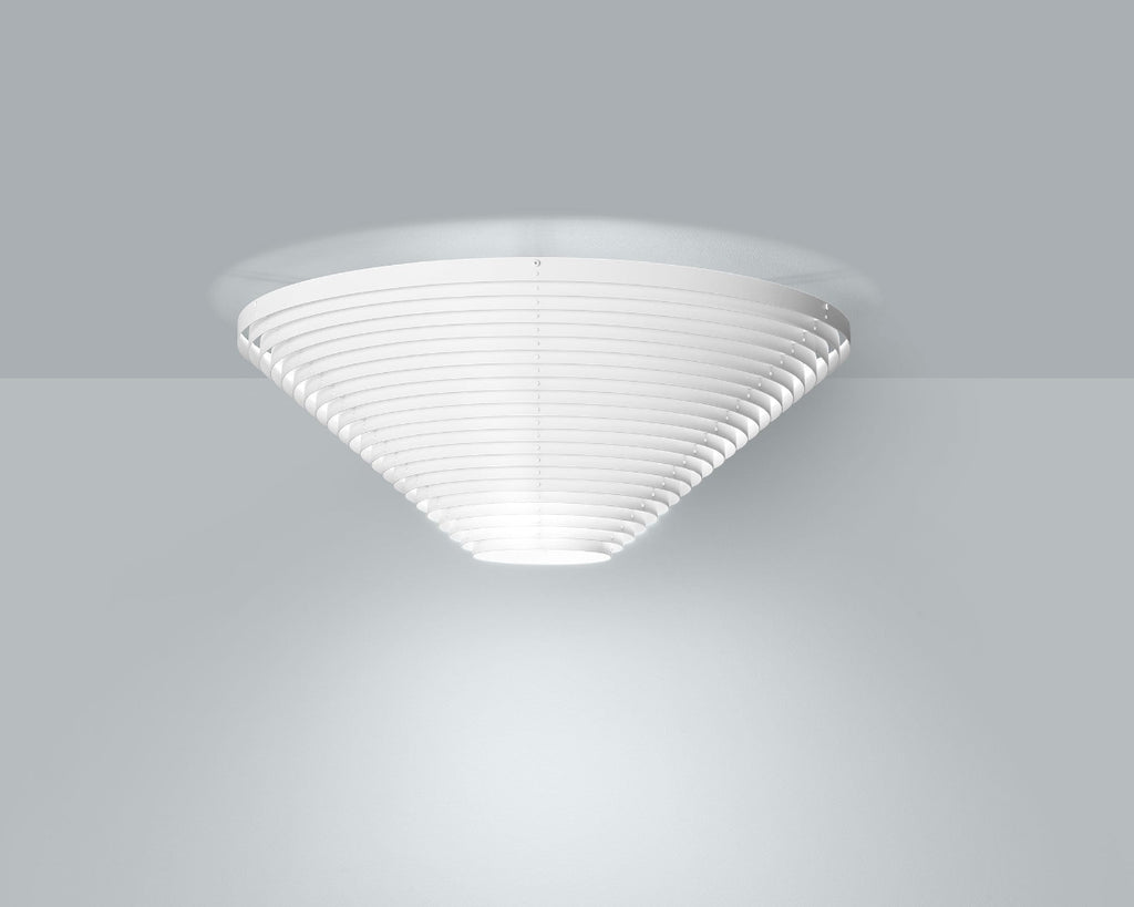 Product image of white Artek Ceiling Light A622A mounted to the ceiling in a grey space. The ceiling light is switched on, emitting light.