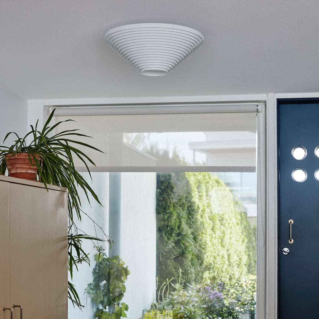 Interior view of a hallway featuring Ceiling Light A622B mounted on the ceiling. A blue entrance door and a large window are visible, with plants seen outside. The light is switched off.
