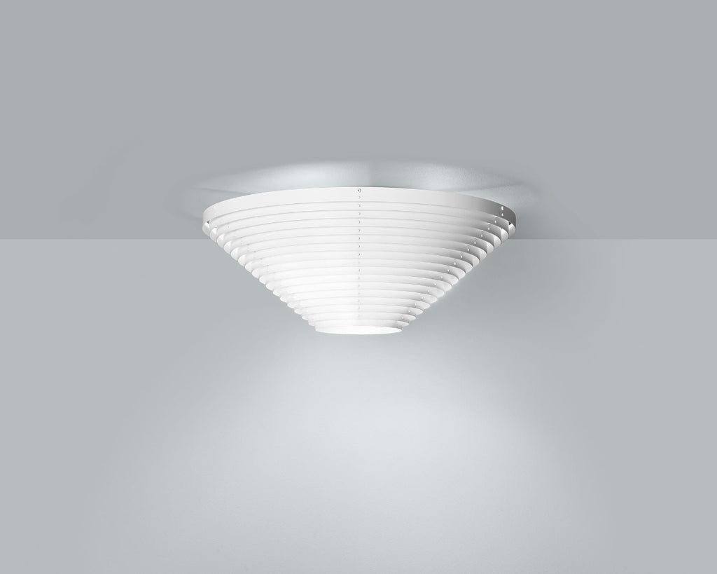Product image of white Artek Ceiling Light A622B mounted to the ceiling in a grey space. The smaller ceiling light is switched on, emitting light.