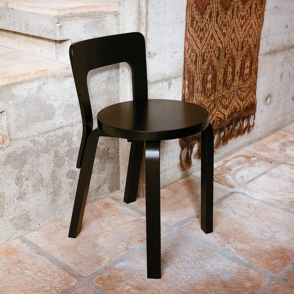 Interior view featuring Artek Chair 65 in black lacquer placed in a minimalist grey space.
