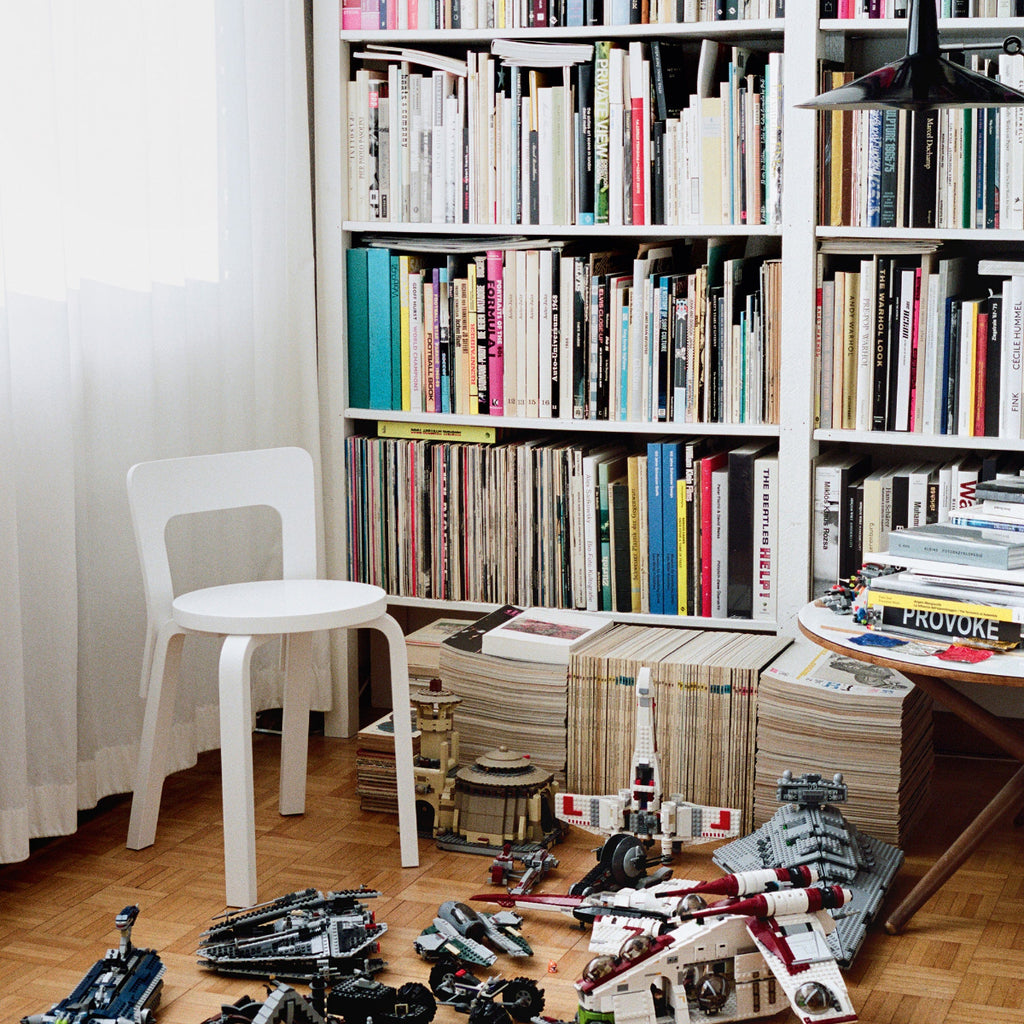Interior view featuring Artek Chair 65 in white lacquer placed in a children’s room. In the background, a bookcase filled with books and magazines is visible, with Lego pieces scattered on the floor.