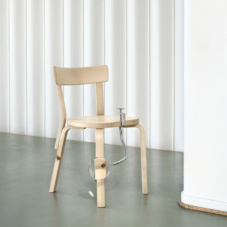 Interior view featuring Chair 69 in wild birch, with a magnifying glass highlighting a knot detail in the wood.