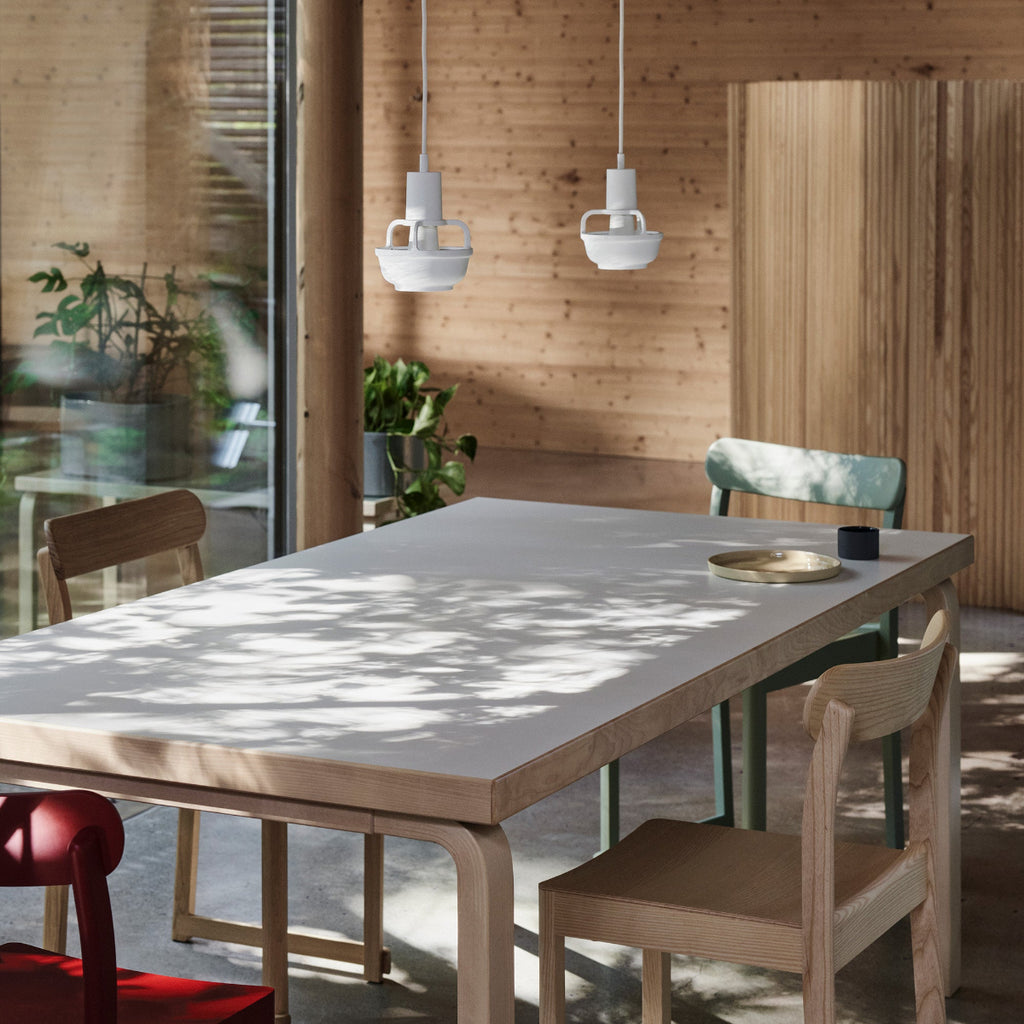 Interior view of a cottage dining area featuring Aalto Table 83 surrounded by Atelier Chairs. Two white Kori Pendant Light hang above the table.