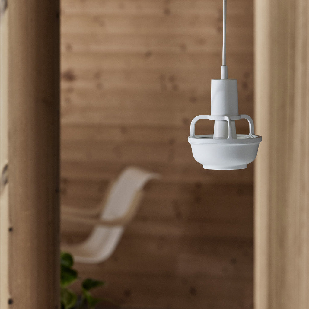 Interior view of a cottage space lit by daylight featuring Kori Pendant Light switched on. In the background, Armchair 42 is visible.
