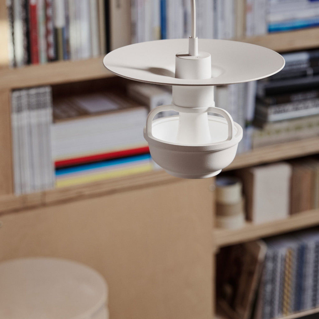 Close-up interior view featuring Kori Pendant Light with Disc Shade. A bookcase with books is visible in the background.