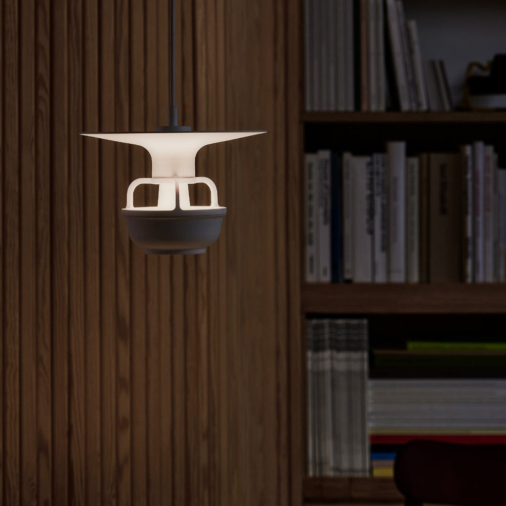 Interior view of a dark space featuring Kori Pendant Light with Disc Shade. A bookcase filled with books is visible in the background, along with part of Screen 100.