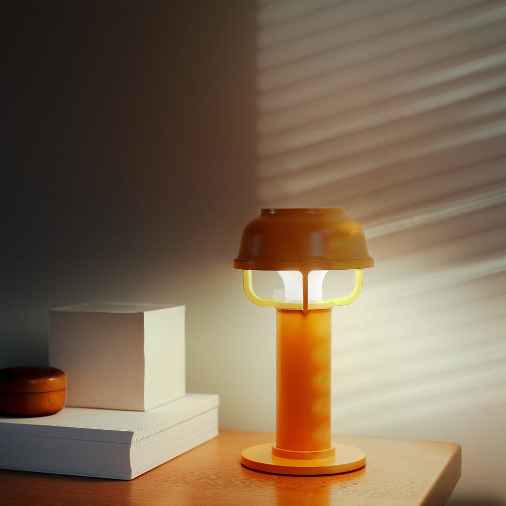 Interior view featuring an orange Kori Table Light switched on, placed on a bedside table.