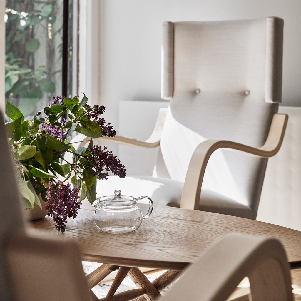 Close-up interior view featuring an oak Ovalette Table, with Armchair 401 visible in the background.