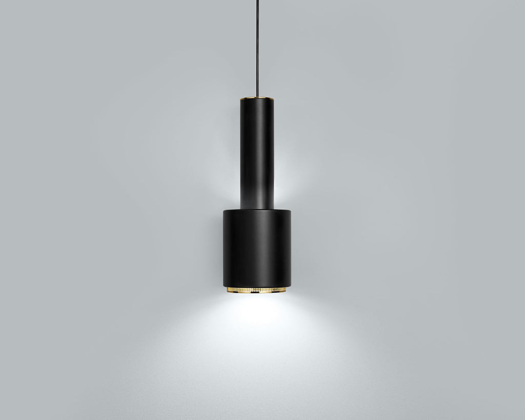 Product image of black Artek Pendant Light A110 “Hand Grenade” with brass details. The pendant light is switched on and photographed against a grey background.