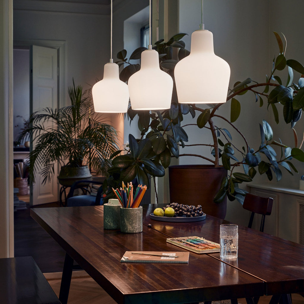 Interior view of a dimly lit dining area featuring Pirkka Table with three Pendant Light A440 switched on above it.