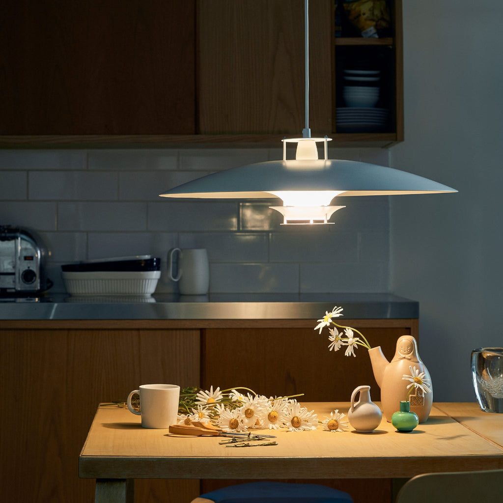 Interior view of a dimly lit kitchen featuring white Pendant Light JL341 switched on above an old table.