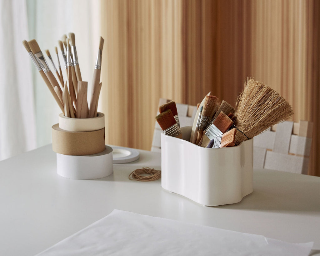 Interior view featuring Artek Table 97 with a white Riihitie Plant Pot placed on the tabletop. The plant pot holds paintbrushes.
