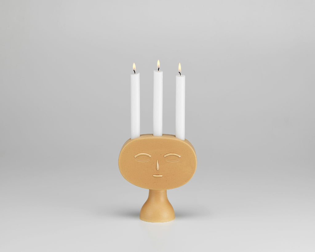 Product image of Artek Secrets of Finland Lucia Candleholder with lit candles, photographed against a grey background.