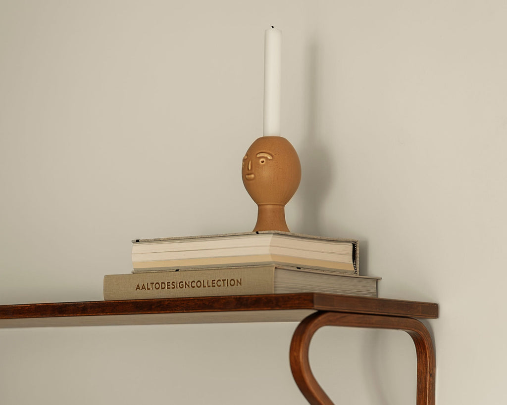 Interior view featuring Artek Secrets of Finland Lucius Candleholder placed on a stack of books on Wall Shelf 112B.