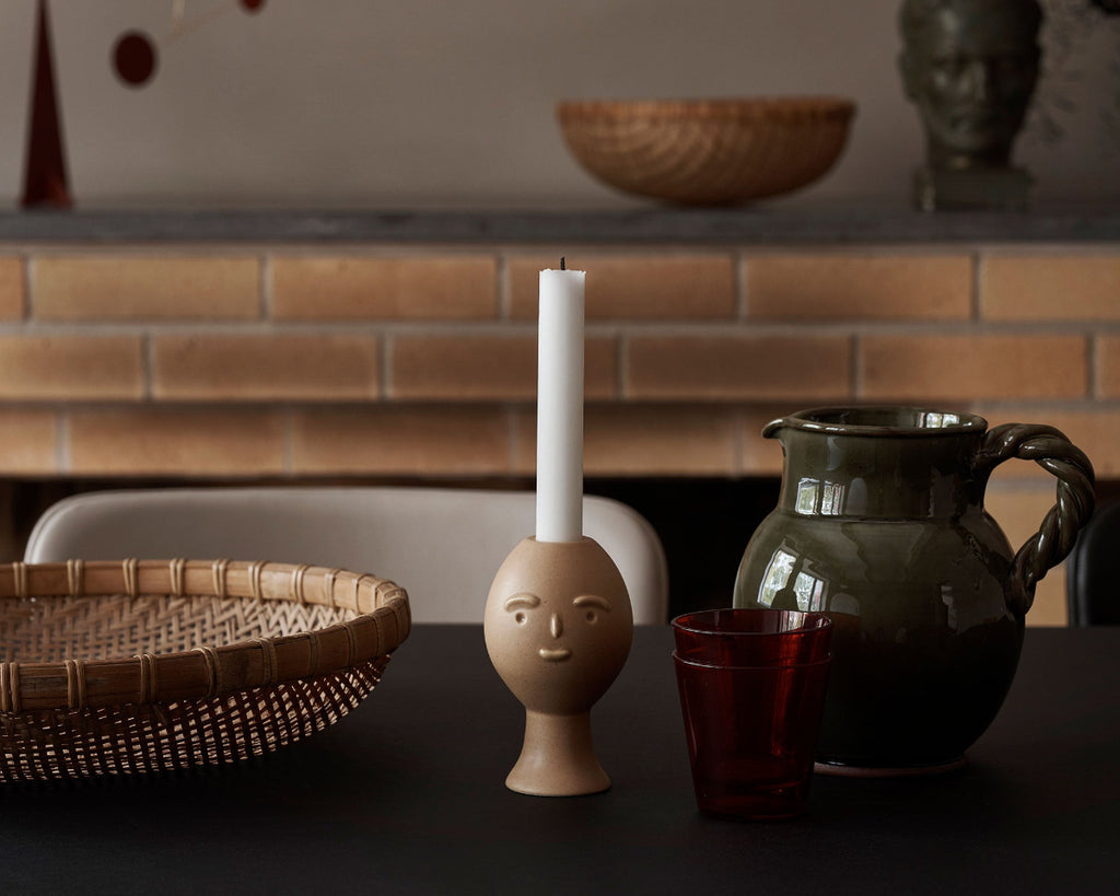 Close-up interior view of Artek Secrets of Finland Lucius Candleholder placed on a table. A fireplace is visible in the background.