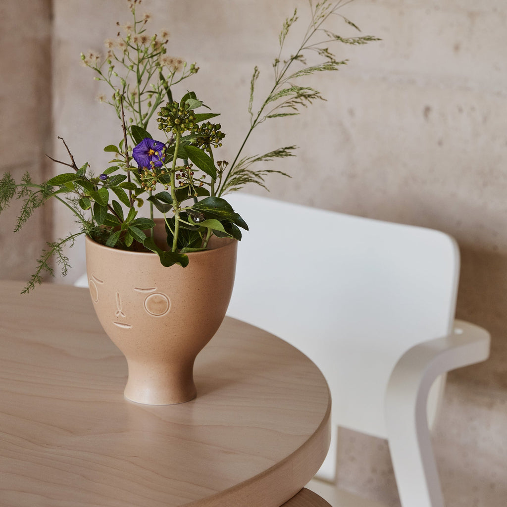Interior view featuring Secrets of Finland Midsummer Dream Vase placed on a table, with flowers arranged inside. A white Aslak Chair is visible in the background.