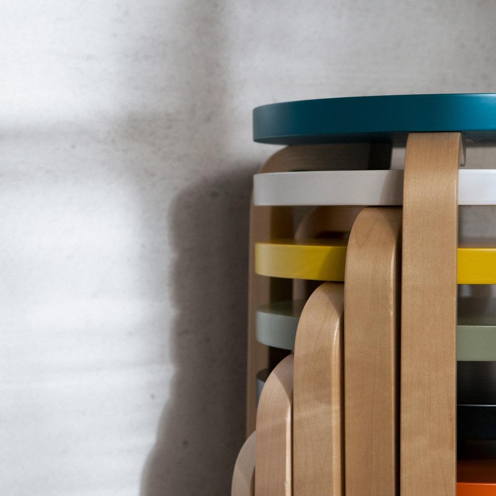 Close-up interior view of a stack of Artek Stool 60. The stools are stacked, with seats featuring different coloured tops.