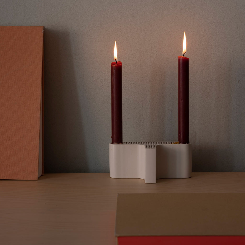 Close-up interior view featuring white Tiili Candleholder with red candles burning.