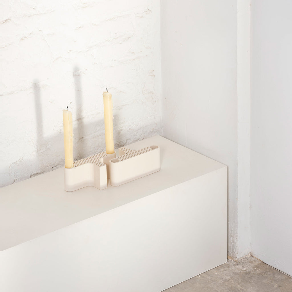 Interior view of a white room featuring two white Tiili Candleholder placed on a white surface.