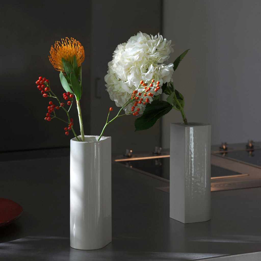 Interior view featuring two white Tiili Vase placed on a kitchen counter, each holding branches with flowers.