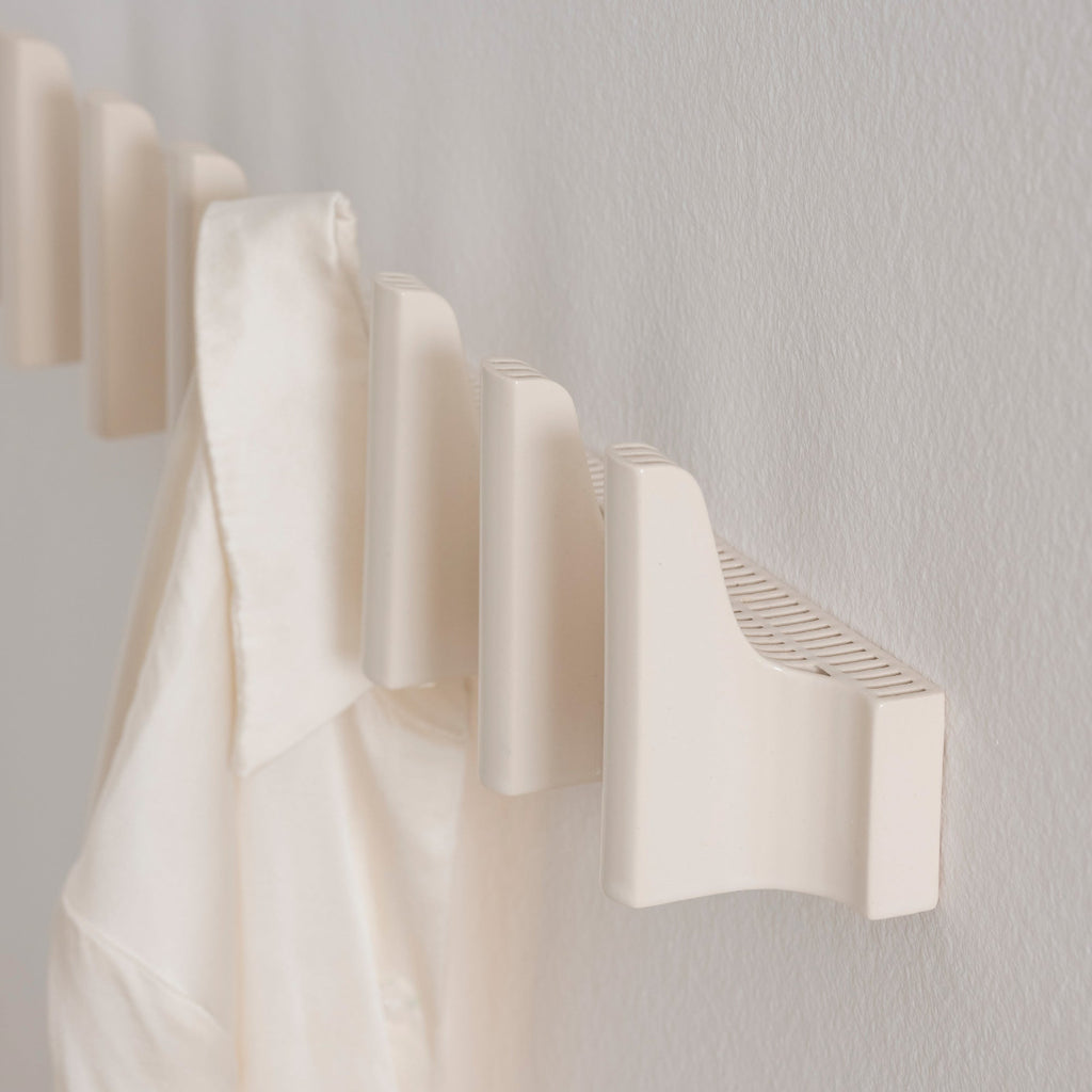 Close-up interior view featuring multiple white Tiili Wall Hooks mounted on a wall.