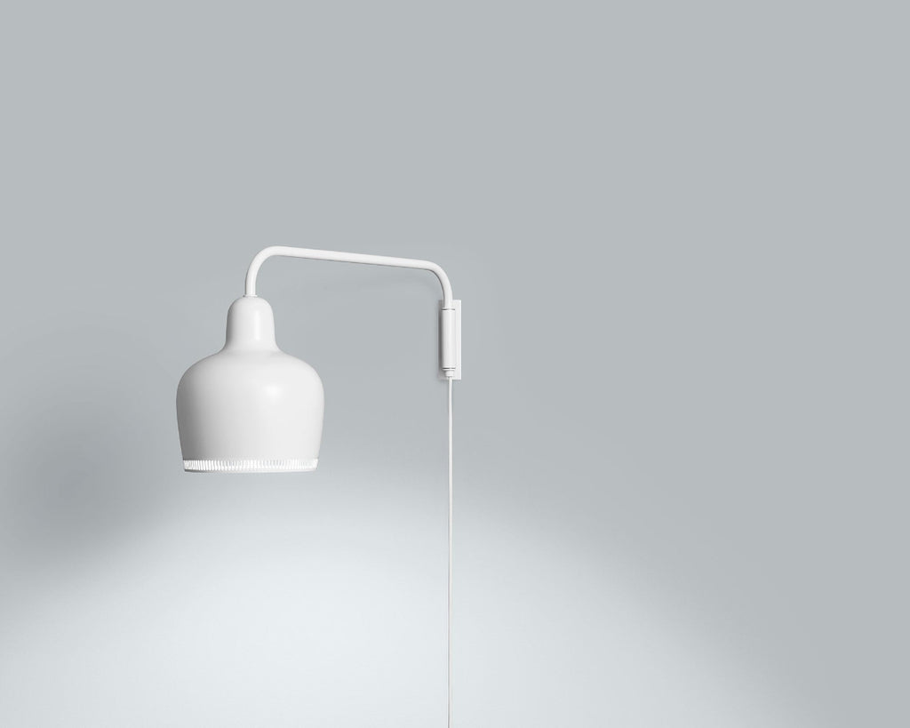 Product image of white Artek Wall Light A330S “Golden Bell”. The wall light is switched on and photographed against a grey background.